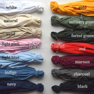May include: A collection of 14 t-shirts in various colors, including white, natural, gold, military green, sand, forest green, light pink, red, light blue, maroon, indigo, charcoal, navy, and black. The t-shirts are folded and arranged in two rows, with the colors alternating.