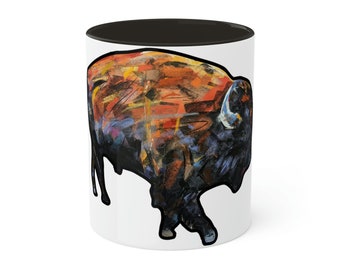 May include: A white ceramic mug with a black interior and a colorful abstract painting of a bison on the front.