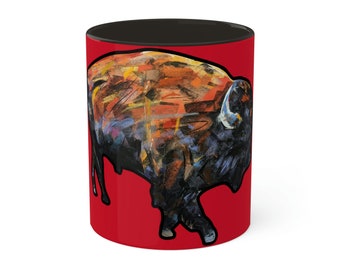 May include: A ceramic coffee mug with a vibrant abstract painting of a bison. The artwork features a mix of orange, yellow, and black brushstrokes against a red background. The interior of the mug is black.