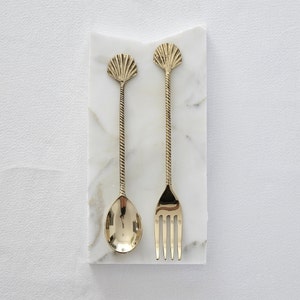 May include: A white ceramic mug with a black handle and the text "But First, Coffee" in a black, bold font. The mug is on a white surface.