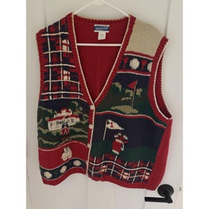 May include: A Pendleton brand V-neck sweater vest featuring a multi-colored knit pattern with golf-themed imagery including flags, golf bags, and plaid sections. The vest is primarily red, navy blue, green, and cream with a button-front closure.