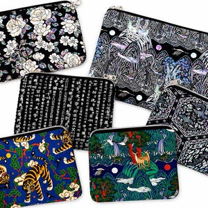 May include: A collection of rectangular zippered pouches with various designs. The pouches feature floral, calligraphic, and landscape patterns in colors like black, white, blue, and gold. The pouches are made of fabric and have silver-toned zippers.