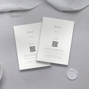 May include: Two white RSVP cards with black text and a QR code. The text reads "N&A" and "Please scan the QR code to RSVP on our wedding website www.ourweddingwebsite.com. Kindly reply by the 16th of September."
