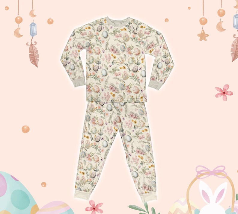 May include: Cream-coloured two-piece pyjama set with a floral and egg pattern. The long-sleeved top and trousers have a relaxed fit with ribbed cuffs and a crew neck. The design features pastel-coloured flowers and Easter eggs, perfect for a cosy night.