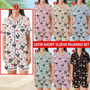 K&ouml;nnte beinhalten: Satin-Pyjama-Sets mit kurzen &Auml;rmeln in verschiedenen Farben, darunter Wei&szlig;, Rosa, Gelb, Blau, Gr&uuml;n, Lila und Schwarz. Jedes Set besteht aus einem passenden Oberteil und Shorts mit einem sich wiederholenden Muster aus Drachen, Rosen und Musikinstrumenten.