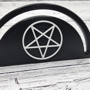 May include: Black and white pentagram design on a black half-circle shaped object.