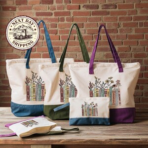 a collection of colorful tote bags and a small bag, all with illustrations of books and flowers printed on them, displayed on a wooden surface against a brick wall.