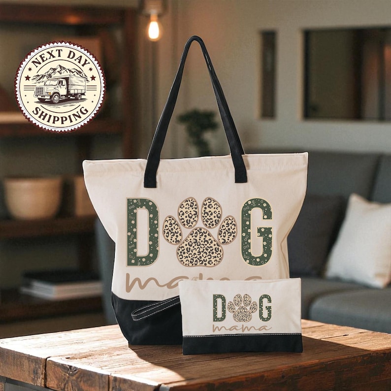 A large tote bag with a leopard print paw print design and the word "dog" printed on it, along with a smaller bag that says "dog mama" on it, both placed on a wooden table.