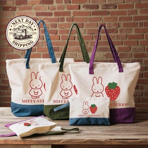 a collection of bags and accessories, including tote bags and a small bag, all with a distinctive design featuring a cartoon rabbit and a strawberry.