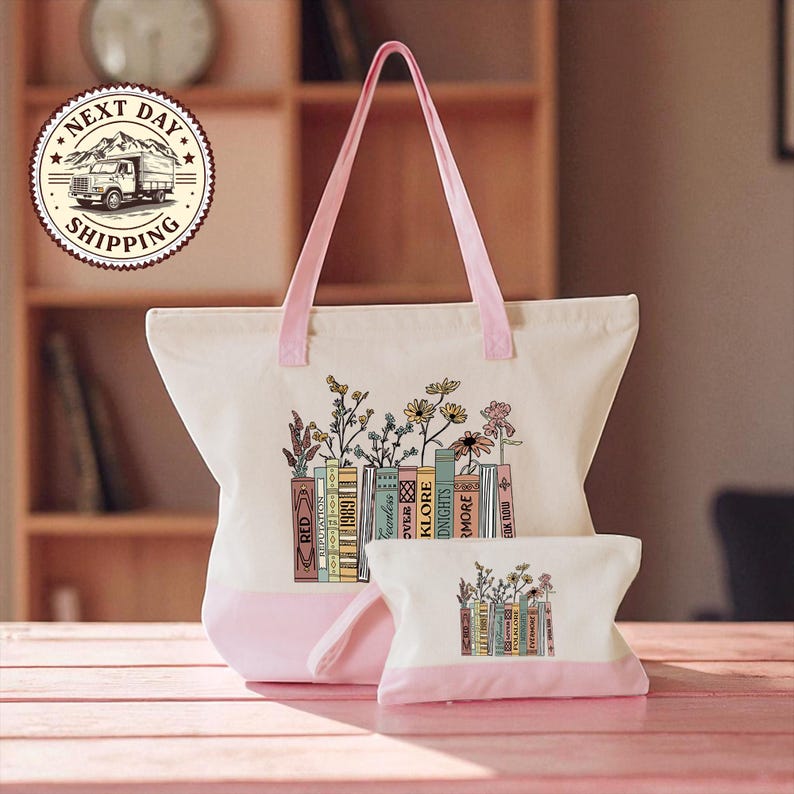 A white tote bag with a pink handle and a smaller bag with a similar design are displayed on a wooden surface.