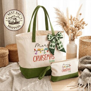 a green and white tote bag with a Christmas-themed design, including a bow and the text "Merry Cruisesmas Emily". The bag is placed on a wooden surface, surrounded by various items such as a vase with dried flowers, a woven basket, and a small white bag.