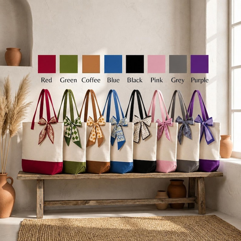 A row of colorful tote bags with bows, each with a different color, displayed on a wooden bench against a white wall.