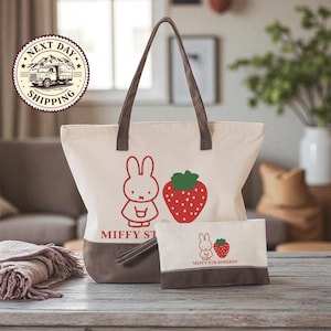 a large tote bag and a smaller bag with a strawberry design, both placed on a wooden surface.