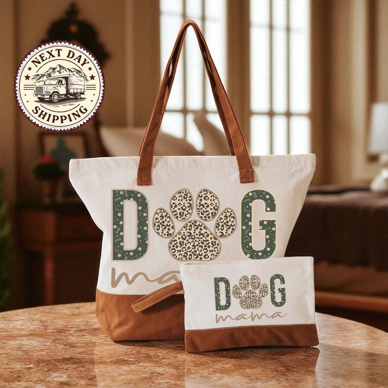 A white tote bag with a leopard print paw print design and the word "dog" printed on it, along with a smaller white bag with the word "dog" printed on it, both placed on a wooden table.