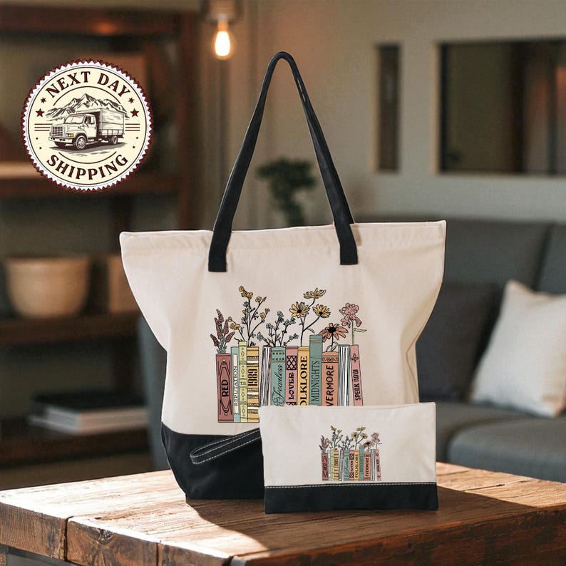 A white tote bag with a floral design and a smaller bag with a similar design are displayed on a wooden table, with a couch and bookshelf in the background.