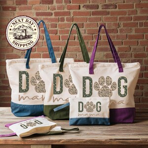 A collection of colorful tote bags with leopard print paw prints, each featuring the word "dog" printed on them. The bags are arranged on a wooden surface, with a brick wall in the background.