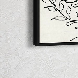 Pu&ograve; includere: Stampa in bianco e nero di arte lineare di un disegno floreale con foglie e steli. La stampa &egrave; incorniciata in una cornice nera.