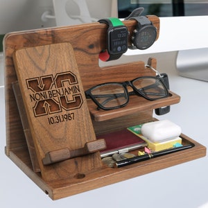 May include: Wooden desktop organizer with a phone stand, watch holder, glasses holder, and a small tray. The organizer is engraved with the text "NONI BENJAMIN XC 10.31.1987".