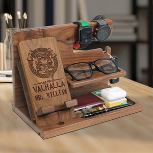 May include: A wooden desktop organizer with a phone stand, watch holder, glasses holder, and a compartment for keys and other small items. The organizer is engraved with the text "See you in Valhalla Mr. William" and a Viking warrior design.
