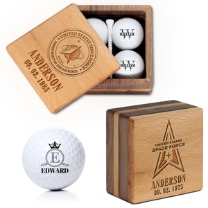 May include: A wooden box with a lid, engraved with the United States Space Force logo and the text "Anderson 09.02.1975". The box contains four golf balls, each engraved with the letter "W" and the name "William".