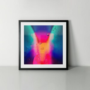 May include: Abstract art print featuring a colourful, iridescent design with a pink, yellow, and blue colour scheme. The design resembles a swirling, abstract pattern with small, white bubbles.