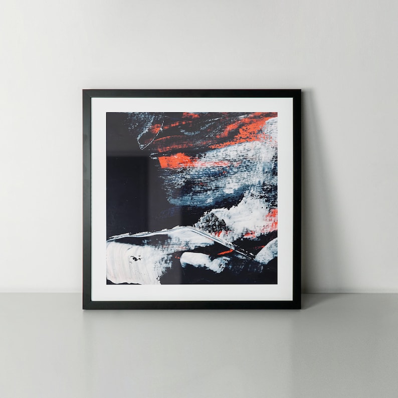 May include: Abstract art print in a black frame. The print features a colourful abstract design with shades of blue, white, and orange.