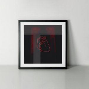 May include: Framed art print featuring a minimalist red outline of a human heart on a black background. The artwork is encased in a black frame with a white mat, creating a striking contrast. The overall aesthetic is modern and artistic.