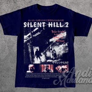 May include: Navy blue t-shirt featuring a graphic from the video game Silent Hill 2. The design includes Japanese text, the game's title, and a scene with figures in a dark hallway. The shirt also has text describing the game's plot.
