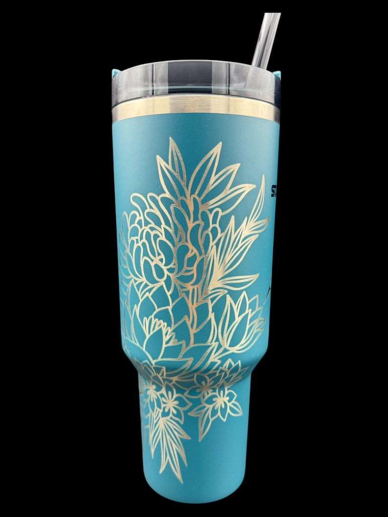 Peut inclure: Un gobelet en acier inoxydable bleu turquoise avec un motif floral dor&eacute;. Le gobelet est dot&eacute; d'un couvercle et d'une paille.