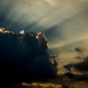 Könnte beinhalten: Ein dunkler, stürmischer Himmel mit Sonnenstrahlen, die durch die Wolken brechen.