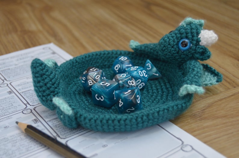 Pu&ograve; includere: Un vassoio da gioco per dadi a forma di drago in crochet color turchese con un corno bianco e un occhio nero. Il vassoio &egrave; pieno di dadi blu e bianchi con i numeri 3, 4, 5, 6, 8, 10, 20 e 30.