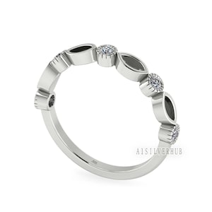 May include: A silver ring with a delicate design featuring alternating oval and round shapes. The ring is set with small clear stones and has a 925 stamp on the inside.