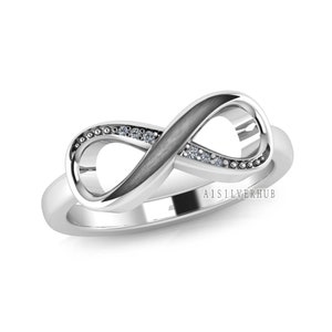 May include: A silver infinity ring with a black inlay and small clear stones set in the band. The ring is a symbol of eternal love and commitment.