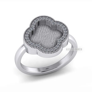 May include: A silver ring with a four-leaf clover design. The clover is outlined with small clear stones and has a hollow center. The ring is marked "925" on the inside band.