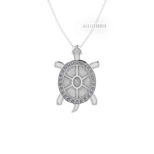 Puede incluir: Collar con colgante de plata en forma de tortuga con una concha incrustada de cristales transparentes. La tortuga es un símbolo de longevidad y buena suerte.