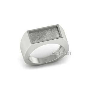 May include: A silver ring with a rectangular, textured, gray inlay. The ring is marked "925" on the inside band. A1SILVERHUB is printed on the ring.