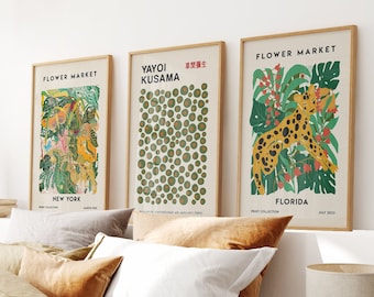 Puede incluir: Tres impresiones de arte enmarcadas con un fondo blanco e ilustraciones coloridas. Las impresiones se titulan "Flower Market", "Yayoi Kusama" y "Flower Market". La primera impresión presenta una ilustración colorida de flores y un leopardo. La segunda impresión presenta un patrón de círculos verdes y dorados. La tercera impresión presenta una ilustración colorida de un leopardo en un entorno de jungla.