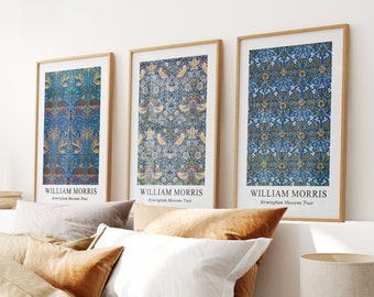 May include: Three framed prints of William Morris designs, featuring intricate floral and bird patterns in shades of blue, yellow, and green. The prints are displayed on a white wall above a bed with brown linen bedding.