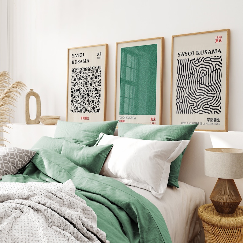 Puede incluir: Tres impresiones enmarcadas de arte abstracto de Yayoi Kusama. Las impresiones son en negro, blanco y verde. Las impresiones est&aacute;n colgadas en una pared blanca sobre una cama con ropa de cama verde.