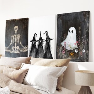 May include: Three black and white witches with pointed hats stand in front of a white background. A black and white skeleton sits in a yoga pose in front of a dark wood background. A white ghost stands in a field of flowers in front of a dark wood background.
