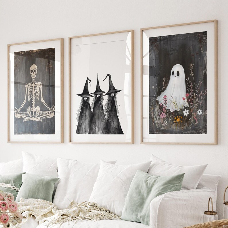 May include: Three framed prints with a Halloween theme. The left print features a skeleton in a yoga pose. The center print shows three witches with black hats and robes. The right print shows a white ghost in a field of flowers.