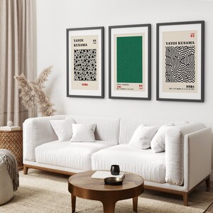 Puede incluir: Tres impresiones de arte enmarcadas con marcos negros y montajes blancos. Las impresiones presentan dise&ntilde;os abstractos en blanco y negro de Yayoi Kusama. Las impresiones est&aacute;n colgadas en una pared blanca sobre un sof&aacute; blanco.
