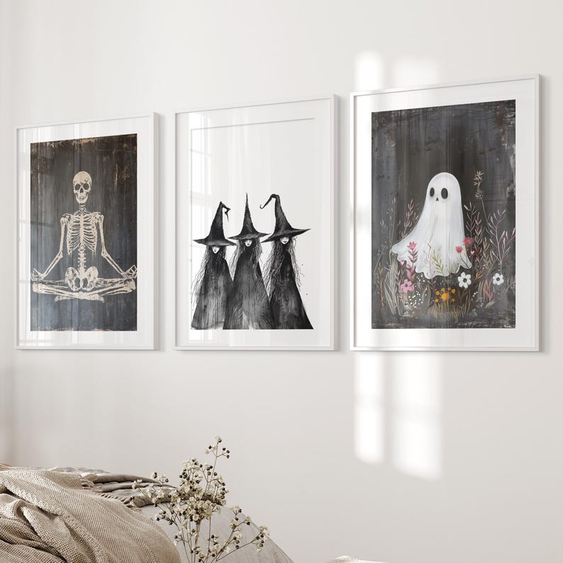May include: Three black and white illustrations in white frames. The left illustration shows a skeleton in a yoga pose. The middle illustration shows three witches wearing black pointed hats. The right illustration shows a white ghost in a field of flowers.