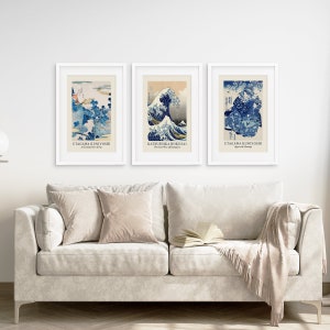 May include: Three framed prints of Japanese woodblock prints. The prints are in blue and white and depict scenes of waves and mountains. The prints are titled "Utagawa Kuniyoshi", "Katsushika Hokusai", and "Utagawa Kuniyoshi".