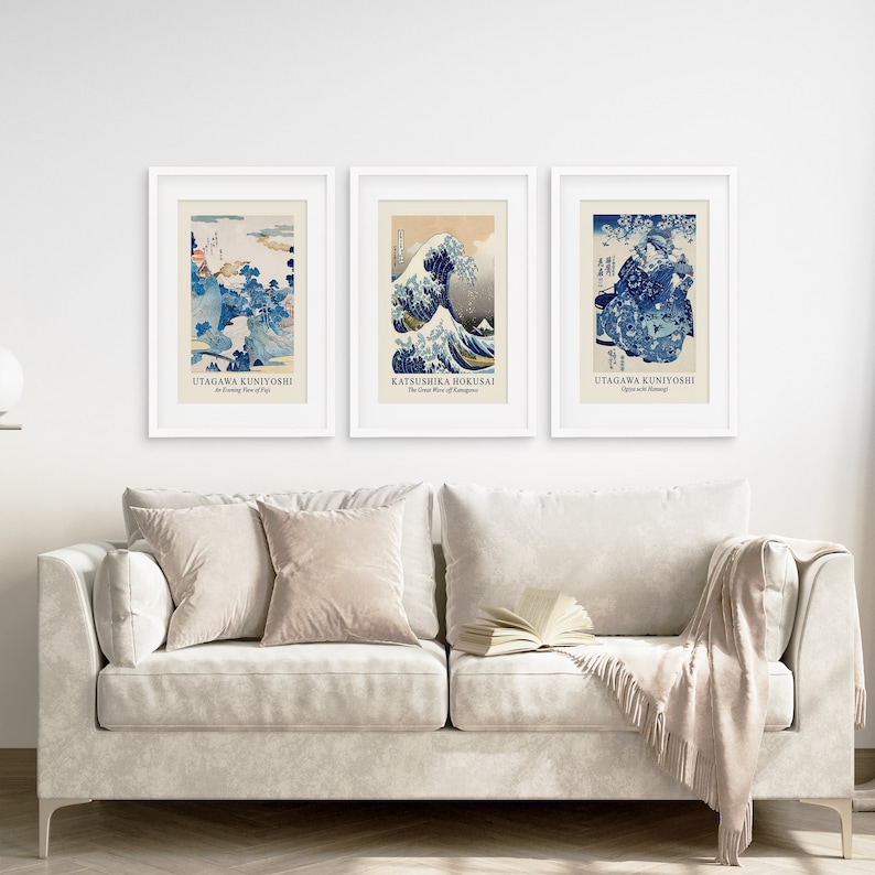 May include: Three framed prints of Japanese woodblock prints. The prints are in blue and white and depict scenes of waves and mountains. The prints are titled "Utagawa Kuniyoshi", "Katsushika Hokusai", and "Utagawa Kuniyoshi".