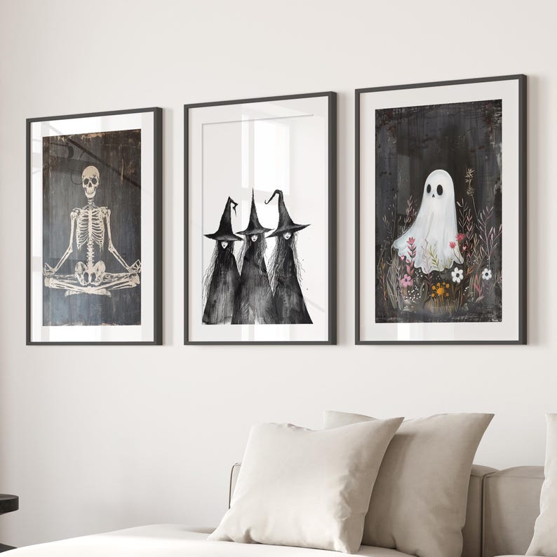 May include: Three black and white illustrations in black frames. The first illustration shows a skeleton sitting in a yoga pose. The second illustration shows three witches wearing black pointed hats and robes. The third illustration shows a white ghost with a black background and pink flowers.