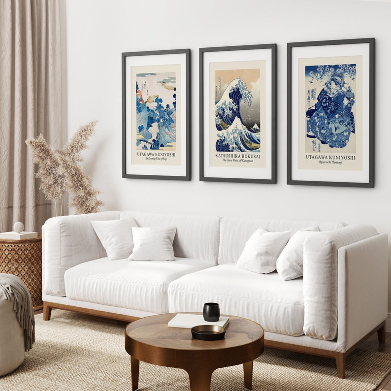 May include: Three framed prints of Japanese woodblock prints. The prints are in black frames and feature blue and white designs. The prints are titled "The Great Wave off Kanagawa" by Katsushika Hokusai, "An Evening Snow at Yaga" by Utagawa Kuniyoshi, and "Ojiya and Aomori" by Utagawa Kuniyoshi.