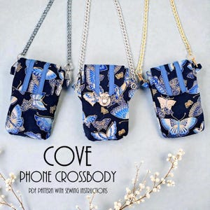 Puede incluir: Tres bolsos cruzados para teléfono de color azul marino con estampados de mariposas y correas de cadena. Cada bolso tiene una franja azul y un cierre de broche. El texto "COVE PHONE CROSSBODY" es visible.
