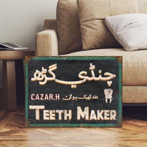 Könnte beinhalten: Ein Schild im Vintage-Stil mit schwarzem Hintergrund und grünem Rand. Das Schild trägt die Aufschrift "Teeth Maker" in weißen Buchstaben und zeigt eine stilisierte Zahngrafik. Die Texte "CAZAR.H" und "سد تہیہ موک" sind ebenfalls in Rot und Weiß sichtbar.