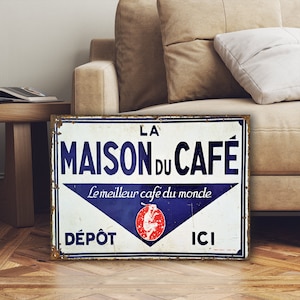以下が含まれることがあります： 「La Maison du Cafe」の広告が書かれたビンテージメタルサイン。フランス語で「Le meilleur cafe du monde」と書いてあり、「Depot」と「Ici」の文字が青と白の配色で書かれている。
